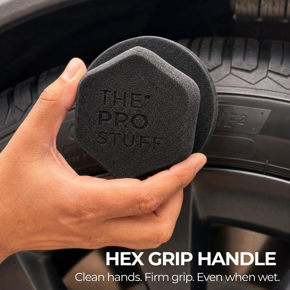 Hand holding the Tire Shine Applicator by its hex grip handle against a tire